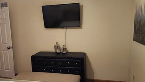 A bedroom with a bed, a dresser, a television mounted on the wall, and a door. - Charming 2-bedroom condo with WiFi, AC in delightful Canton (Canton)