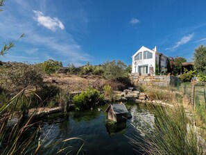 Situated on a serene lakeside setting, this house features a gabled roof and large windows.