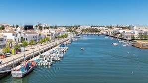 A marina with boats docked along the waterfront, a bridge crossing the water, and buildings lining the shore. - Freesia Villa, Santa Catarina da Fonte do Bispo, Tavira (Stº. Catarina Fonte do Bispo)