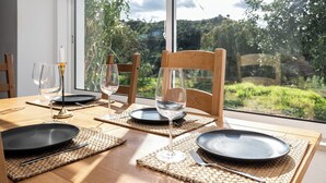 A dining table set with plates, cutlery, and glasses, positioned near a window with a view of greenery and trees. - Freesia Villa, Santa Catarina da Fonte do Bispo, Tavira (Stº. Catarina Fonte do Bispo)