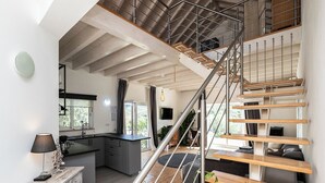 A modern kitchen with a central island, a staircase with wooden steps and metal railings, and a dining area with a table and chairs. - Freesia Villa, Santa Catarina da Fonte do Bispo, Tavira (Stº. Catarina Fonte do Bispo)