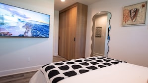 A bedroom with a large bed, a wooden wardrobe, a mirror, and a painting on the wall.