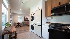 A modern kitchen with a built-in washer and dryer, a large stove, and a dining area with a table and chairs.