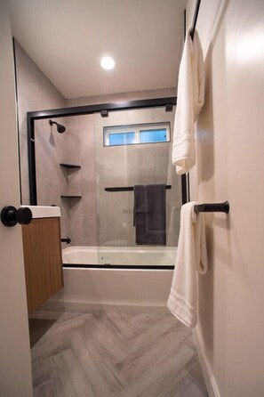 Un baño moderno con ducha envuelta en vidrio, un armario de madera y un perchero.