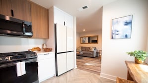 Una cocina moderna con estufa, microondas y refrigerador. Cuenta con un comedor con mesa y sillas.