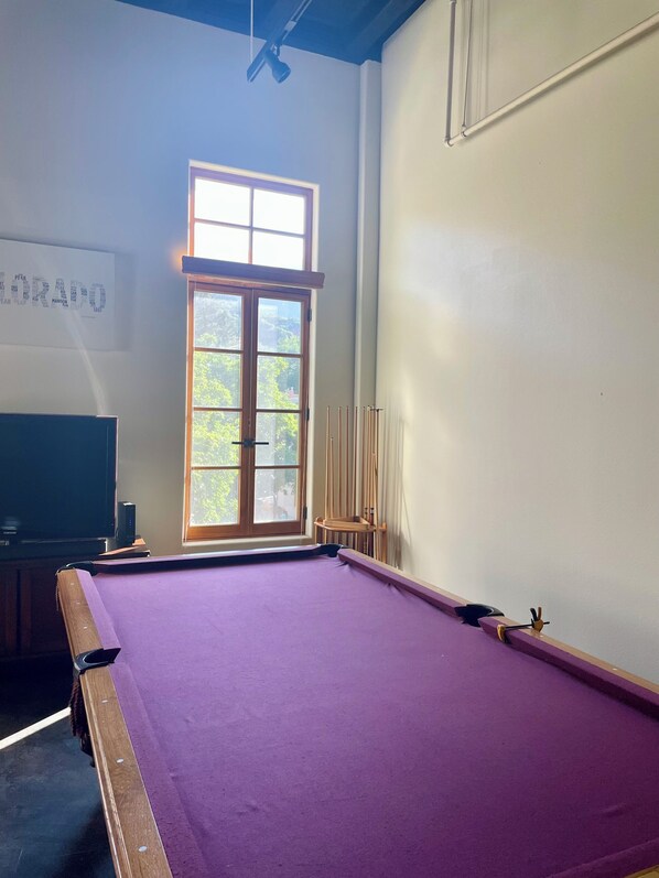 A room with a pool table, a window with a view of greenery, and a television. - Manitou Incline Retreat
(Manitou Springs)