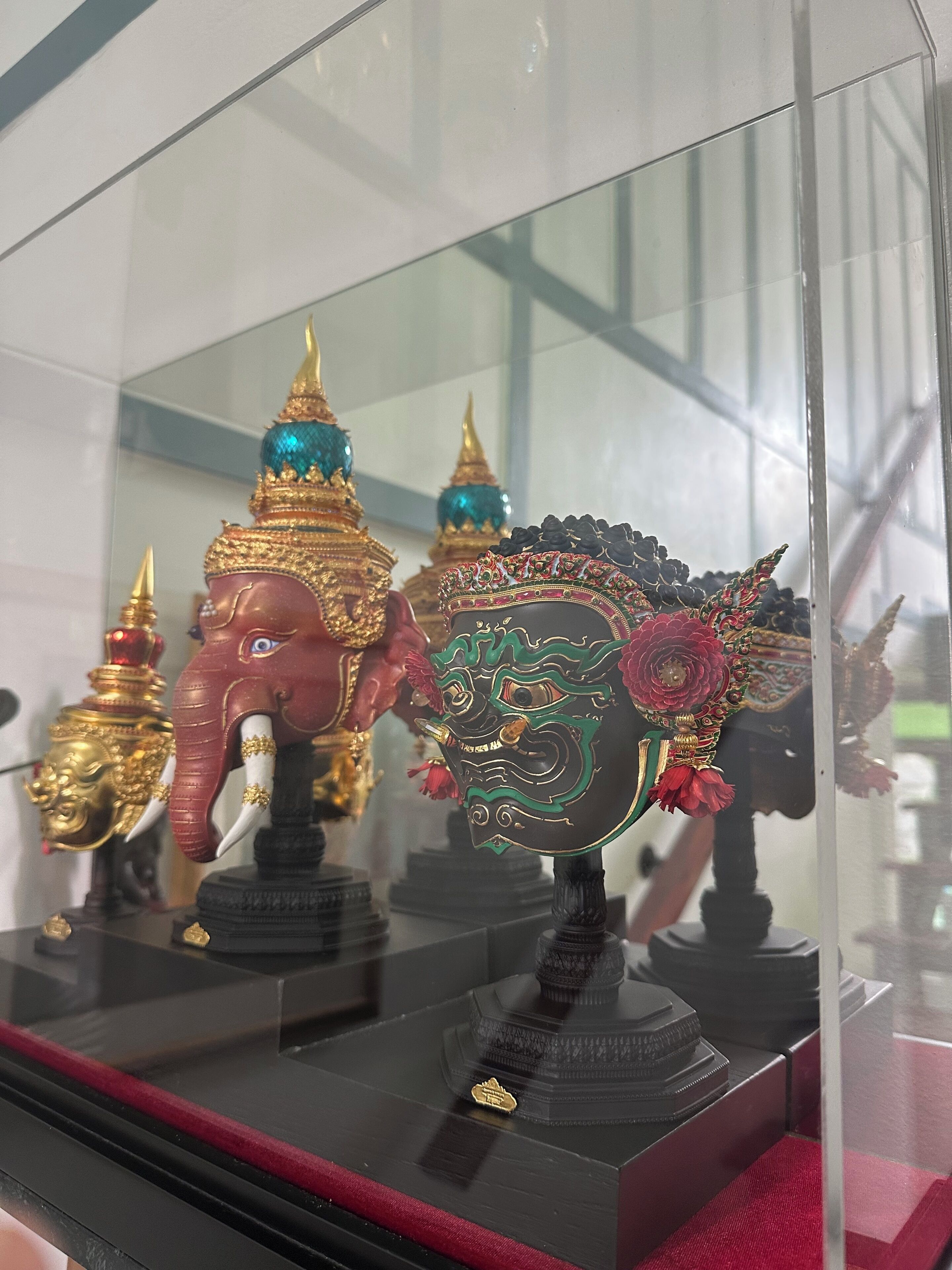 Een vitrine met standbeelden van olifanten en een decoratief hoofdtoek.
