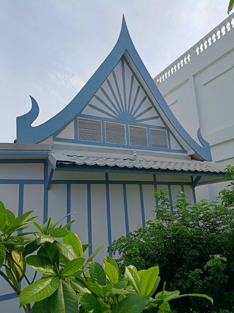 Un edificio con techo a dos aguas, detalles decorativos y pared blanca.