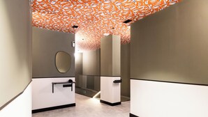 A modern hallway with a patterned ceiling, a handrail, and a mirror on the wall. - Calma Rooms by Charming (Madrid)