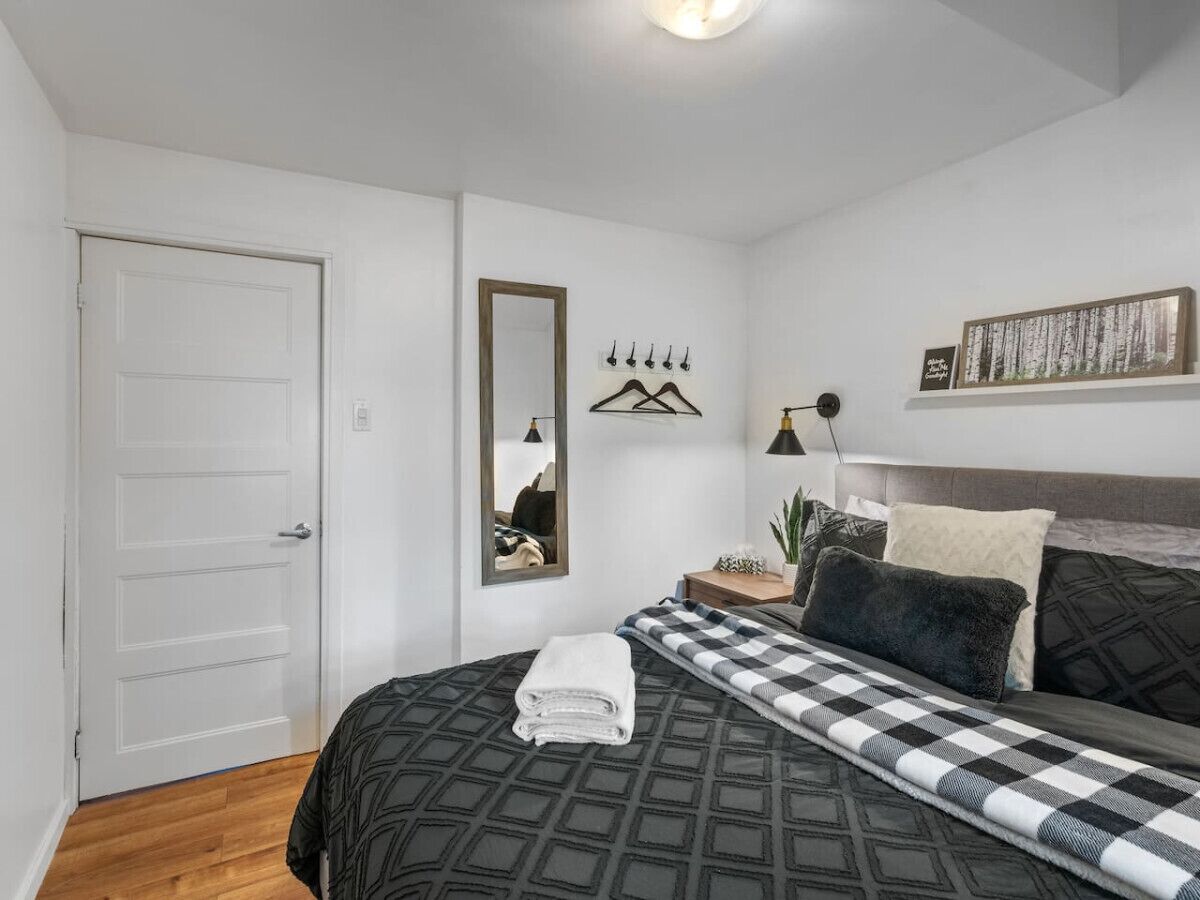 Una camera da letto con un letto, un comodino, uno specchio, una lampada a sospensione e un quadro appeso al muro.