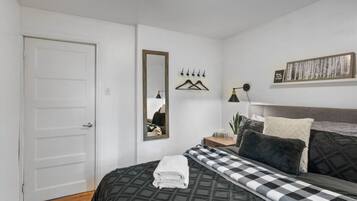 Una camera da letto con un letto, un comodino, uno specchio, una lampada a sospensione e un quadro appeso al muro.