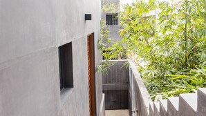 A concrete staircase leading to a door with a small window, surrounded by a low wall and greenery. - Privé Turquoise  (Tulum)