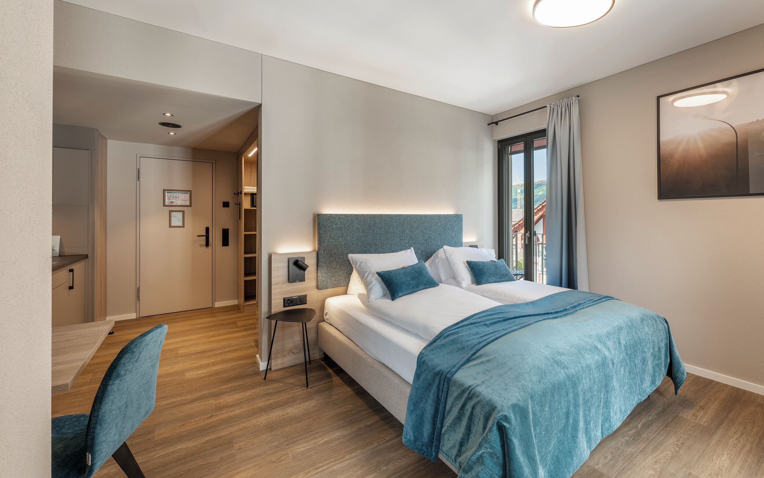 Et moderne hotelværelse med en stor seng, et skrivebord og en stol. Der er udsigt til det fri gennem vinduet.