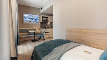 Une chambre d’hôtel comprenant un lit, un bureau avec une chaise, une télévision et une kitchenette.