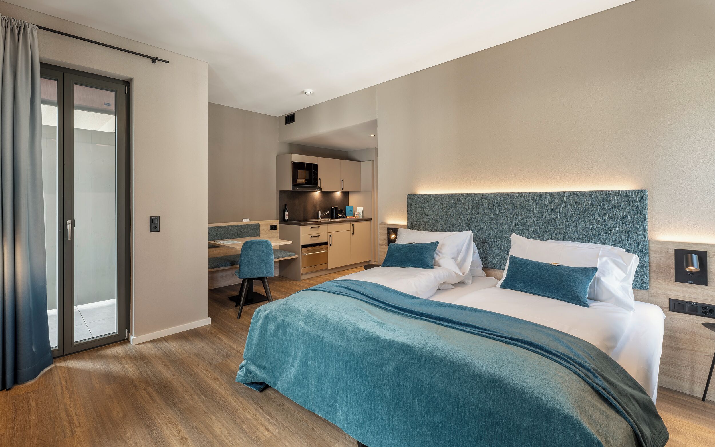 Una habitación de hotel moderna con una cama grande, un escritorio y una kitchenette.