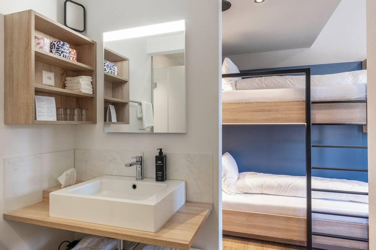 A modern bathroom with a large sink, wooden shelves, and a mirror.