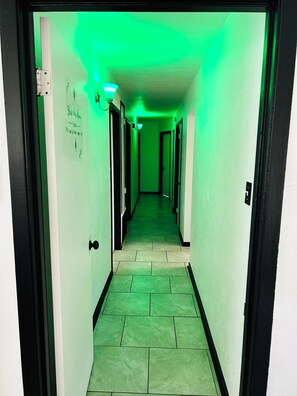 A hallway with green lighting, tiled floor, and doors on both sides. - The Greenhouse Effect- central+ 4BR/2BA+ king suite+ coffee+ BBQ grill (Corpus Christi)