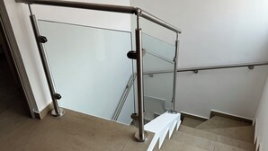 A staircase with glass railings and a metal handrail.