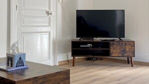 A room with a wooden desk, a television on a wooden stand, and a white door.