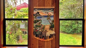 Une tapisserie représentant une scène de plage, suspendue entre deux fenêtres.