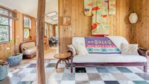 Une pièce chaleureuse avec un mur en bois, un canapé, un tapis à motifs et une grande fenêtre.