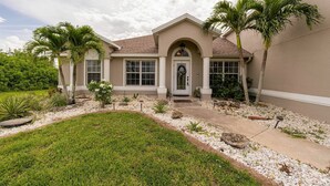 A two-story house with a front porch, palm trees, and a well-maintained lawn. - Sunset Serenity in Port Charlotte (Port Charlotte)