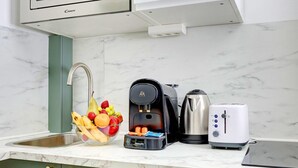 A kitchen with a marble countertop, a coffee maker, a kettle, a toaster, and a fruit bowl. - TheBlueStay 244 - Stylish Studio - Paris 12 (Paris)