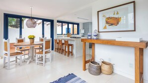 A modern kitchen with a central island, wooden chairs, and a dining table. - House in Búzios less than 100m from the beach (Vila Luiza Armação dos Búzios)