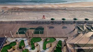 Ranta, jossa on tenniskenttä, aurinkovarjoja ja pelastustorni.