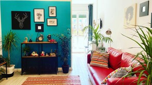 A living room with a teal wall, a red sofa, and various framed artworks. - Cozy Vintage Apartment in Trastevere within walking distance of downtown  (Roma)