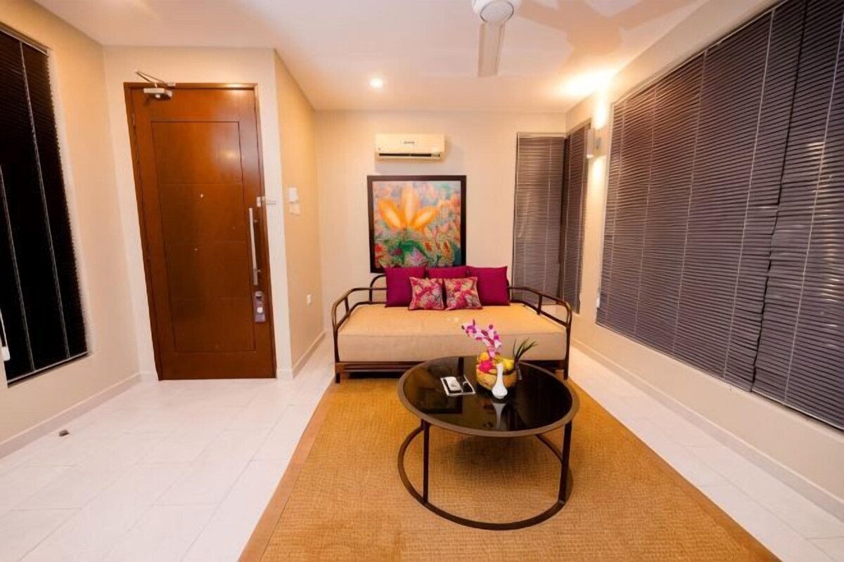 A room with a sofa, a coffee table, a door, and a window with blinds.