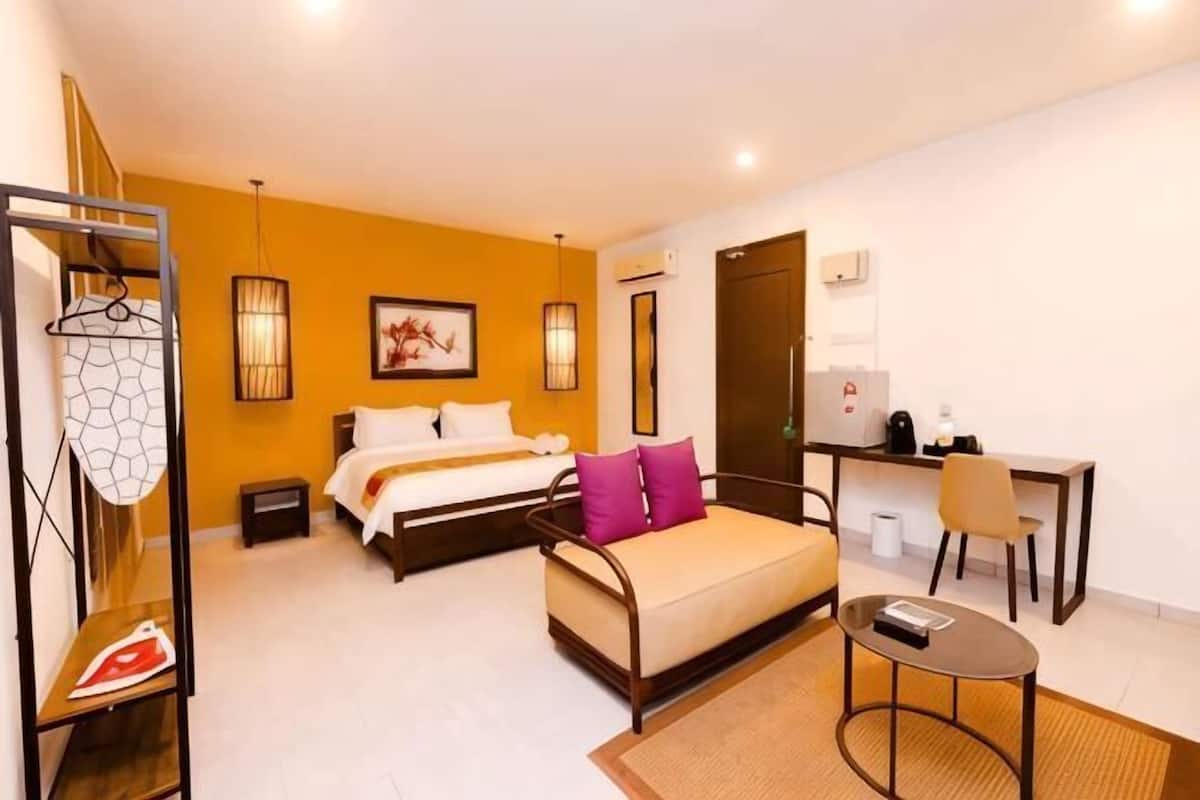 Habitació d'hotel amb un llit, escriptori, cadira, armari i penjador.