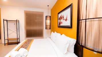 A hotel room with a bed, a window with blinds, a wall-mounted artwork, and a standing lamp.