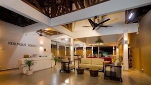 A hotel lobby with a reception desk, seating area, ceiling fans, and a large window. - Rebungan Resort Langkawi (Langkawi)