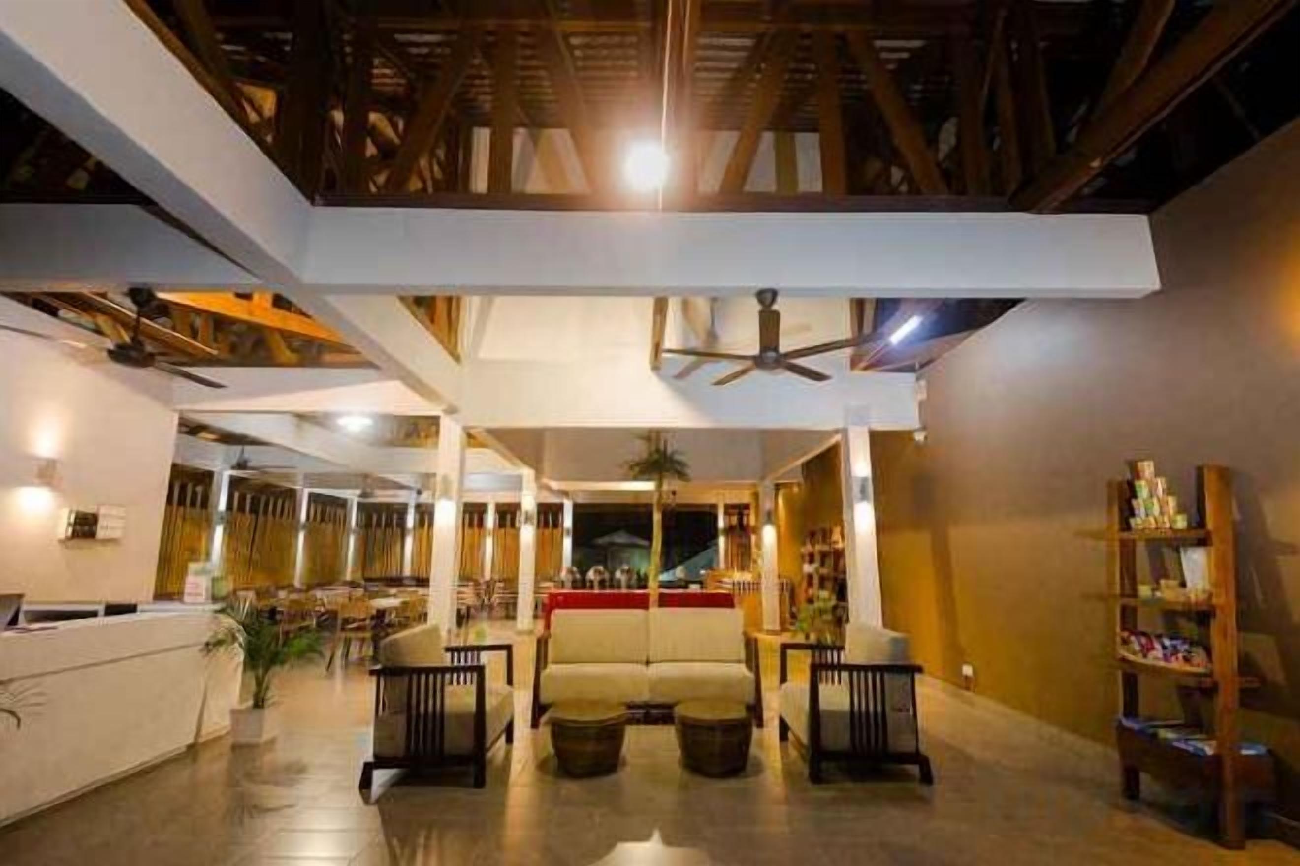 A spacious lobby with a high ceiling, a reception desk, seating area, and a staircase leading to upper floors.