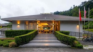 A modern building with a covered entrance, steps leading up to it, and a well-maintained garden. - Rebungan Resort Langkawi (Langkawi)