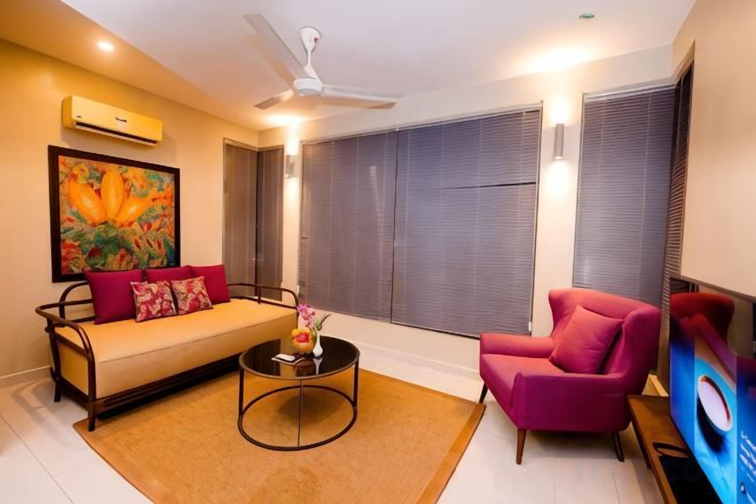 A living room with a sofa, armchair, coffee table, and artwork.