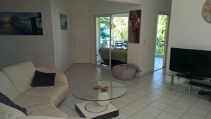 Ein modernes Wohnzimmer mit einem weißen Sofa, einem Glastisch und einem Flachbildfernseher.