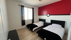 Habitación de hotel con dos camas, un escritorio pequeño y una ventana con cortinas.