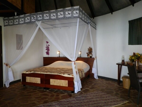 Un dormitorio con cama con dosel, una mesita de noche con lámpara y una silla.