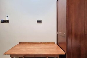A wooden table in a room with a wall-mounted telephone and a small electronic device. - Global Residency (Kota Kinabalu)