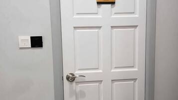 A white door with a doorbell and a sign above it.