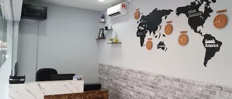 A reception area with a marble reception desk, a world map with clocks, and a brick accent wall.