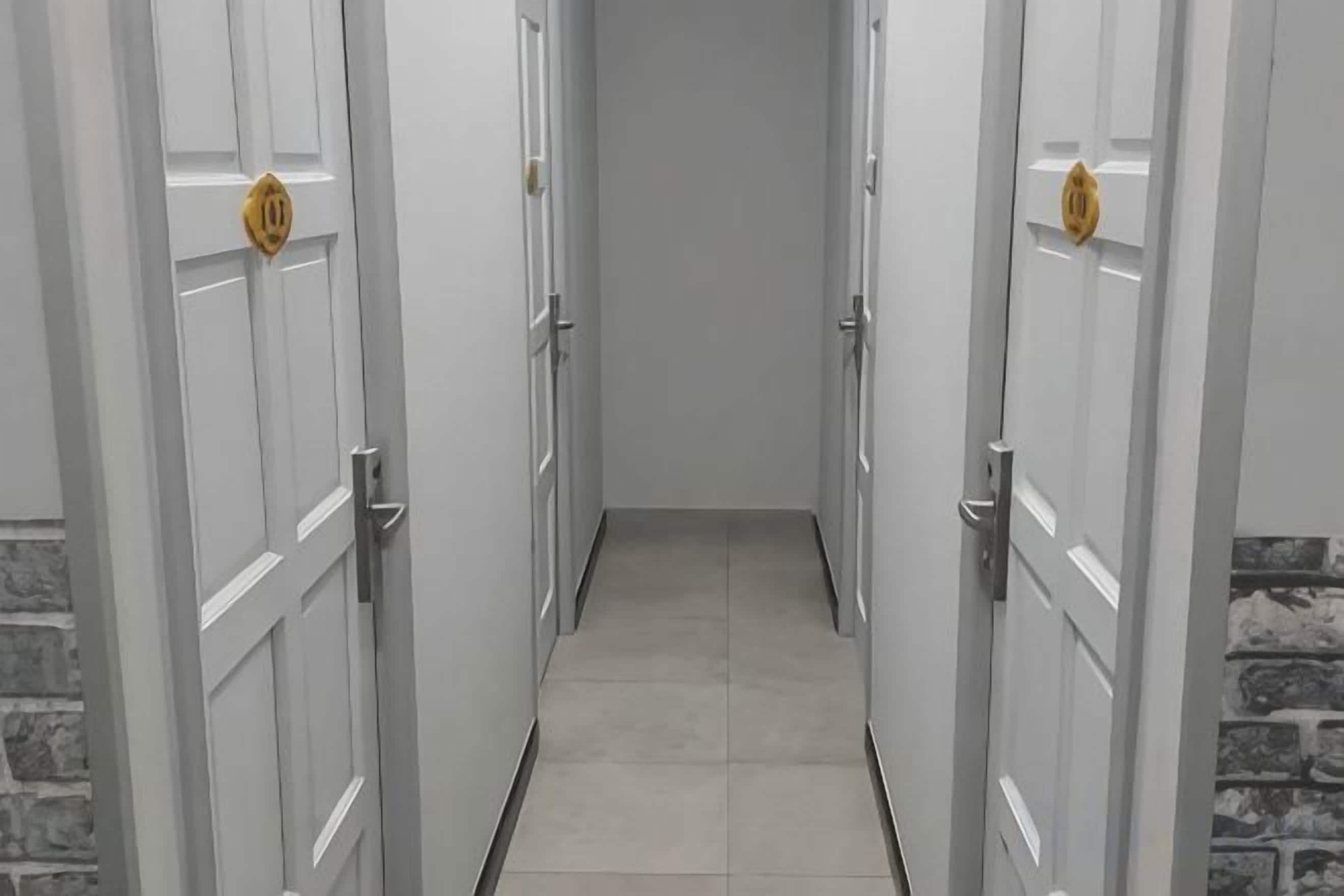 A corridor with white doors, each with a golden handle, leading to a room.