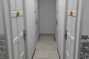 A corridor with white doors, each with a golden handle, leading to a room. - Global Residency (Kota Kinabalu)