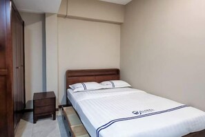 A single bed with a wooden headboard, a small bedside table, and a wardrobe. - Global Residency (Kota Kinabalu)