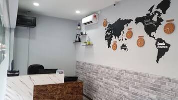 A reception area with a marble reception desk, a black office chair, a world map on the wall, and a brick accent wall.