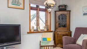 Un soggiorno con televisione, un mobile in legno, una poltrona viola e un tavolo da scacchi.