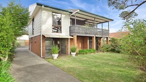A two-story house with a balcony, a paved driveway, and a well-maintained lawn.