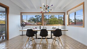 A dining area with a table set for four, large windows, and a ceiling fan.